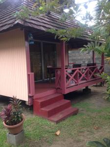 une terrasse couverte avec une table et des escaliers menant à une maison dans l'établissement Fare Aute Beach, à Vaianae