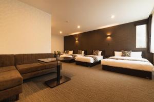 a hotel room with two beds and a couch at GRAND BASE Nagasaki Ekimae in Nagasaki