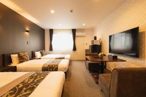 um quarto de hotel com duas camas e uma televisão de ecrã plano em GRAND BASE Nagasaki Ekimae em Nagasaki