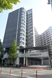 un grand bâtiment avec un parking en face de celui-ci dans l'établissement HEARTS Capsule Hotel & Spa HAKATA, à Fukuoka