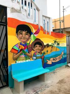 a mural of two children sitting on a bench at Estudios Rehilete in Holbox Island