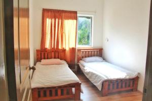 two beds in a room with a window at Cameron Highland Guesthouse in Tanah Rata