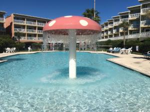 una fuente en una piscina con una sombrilla en el agua en The Victorian Condo/Hotel, en Galveston