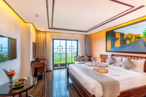 a bedroom with a large bed and a table at Fivitel Hoi An Hotel in Hoi An