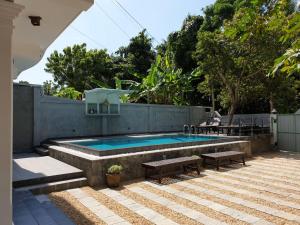 a swimming pool with benches next to a fence at Villa Goodwill Paradise in Hikkaduwa
