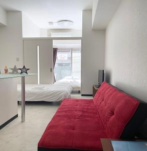 ein Wohnzimmer mit einem roten Sofa und einem Bett in der Unterkunft Lion Tsurumi in Hiroshima