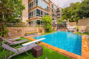 a swimming pool with lounge chairs and a building at Karon View Apartments in Karon Beach