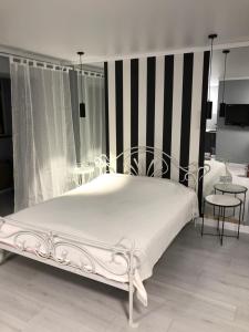 a bedroom with a white bed with black and white stripes at Charming studio in Pechersk in Kyiv