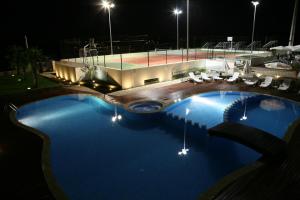 a large swimming pool with a tennis court at night at Quinta Do Passal in Paços de Ferreira