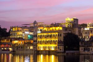 a lit up building on the water at night at Hotel Sarovar On Lake Pichola in Udaipur