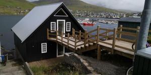 a black house with a porch and a dock at Løðupakkhúsið - LPH - Mid Floor in Sørvágur
