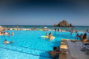 eine Gruppe von Personen im Pool an einem Strand in der Unterkunft Sandy Beach Hotel & Resort in Al Aqah