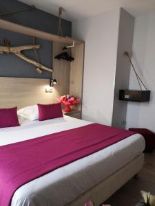 a bedroom with a large bed with purple sheets at Atoll Hotel restaurant in Fréjus