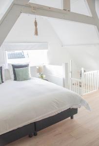 Dormitorio blanco con cama blanca y techo blanco en Tiny House Lindenhouse, en Heemstede