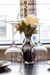 a table with two wine glasses and a vase with a rose at Tiny House Lindenhouse in Heemstede