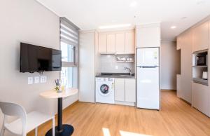 uma pequena cozinha com um frigorífico branco e uma mesa em Hi Residences em Jeju