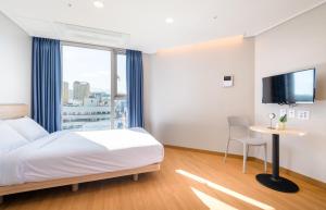 a hotel room with a bed and a table and a tv at Hi Residences in Jeju