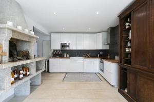 a kitchen with white cabinets and a stone fireplace at Domaine de La Charmille in Ermenonville