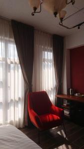 une chaise rouge assise devant une fenêtre de la chambre dans l'établissement Mr. Buster B&B, à Hualien