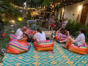 um grupo de pessoas sentadas em cadeiras em um quintal em The Yard Bangkok Hostel em Bangkok