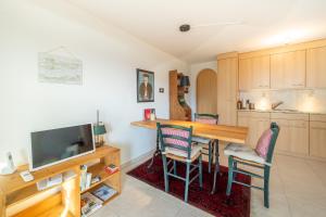 eine Küche mit einem Tisch und Stühlen sowie einem TV in der Unterkunft Casa La Prada in Flims