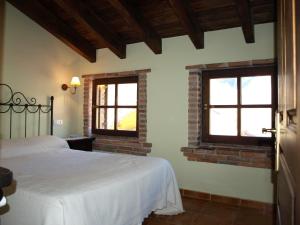 a bedroom with a white bed and two windows at La Currada in Taranes