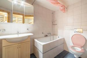 a bathroom with a toilet and a sink and a bath tub at Cristallina II in Laax