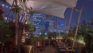 a patio with tables and chairs and a city skyline at night at Kosenda Hotel in Jakarta