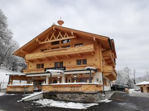 een groot houten gebouw met sneeuw op de grond bij Gasthaus Goglhof in Fügenberg