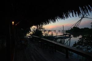a dock with chairs and a boat in the water at Baan​ Tonlamphu​ Pakpra in Phatthalung