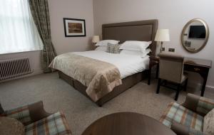 a hotel room with a bed and a table and chairs at Macdonald Old England Hotel & Spa in Bowness-on-Windermere