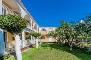 a courtyard of a building with trees and grass at Olga Studios - 3 in Tsilivi