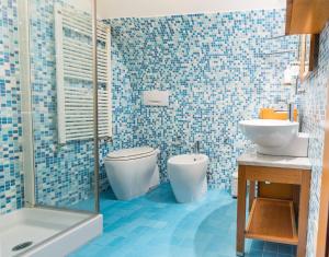 a blue tiled bathroom with a toilet and a sink at Casa Gnostra in Noci