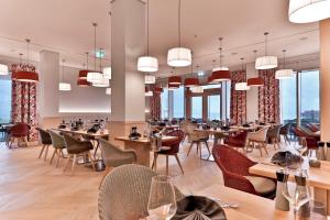 a restaurant with tables and chairs and windows at Upstalsboom Family Suiten und Lofts in Wyk auf Föhr