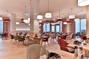 um restaurante com mesas, cadeiras e janelas em Upstalsboom Family Suiten und Lofts em Wyk auf Föhr