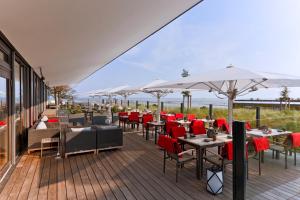 a restaurant with tables and chairs and white umbrellas at Upstalsboom Family Suiten und Lofts in Wyk auf Föhr