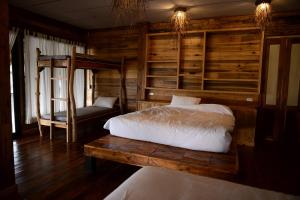 a bedroom with two beds and a wooden wall at Baan​ Tonlamphu​ Pakpra in Phatthalung