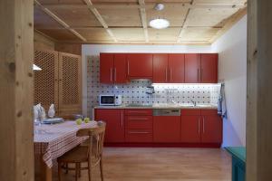 cocina con armarios rojos y mesa en Villa Christina, en San Candido