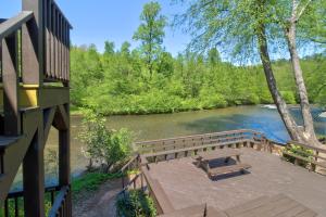 a wooden bench sitting on a deck next to a river at Chattahoochee River Edge Condominiums in Helen