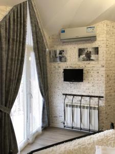 Cette chambre dispose d'une télévision et d'un mur en briques. dans l'établissement Guest House Valeria, à Novgorod