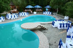 uma piscina com cadeiras e mesas azuis e brancas em Hotel Maria em Botoşani