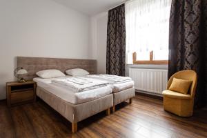 a bedroom with a bed and a chair and a window at Pensjonat Gold Rooms in Koszalin