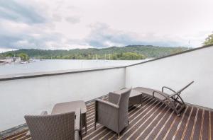 a balcony with chairs and a table and a view of the water at Macdonald Old England Hotel & Spa in Bowness-on-Windermere