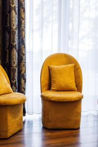 a yellow chair with a pillow sitting next to a window at Gold Rooms in Koszalin