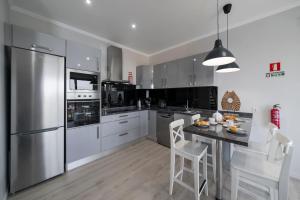 a kitchen with stainless steel appliances and a table with chairs at Vilas Felicidade Rocha by An Island Apart in Ponta do Pargo