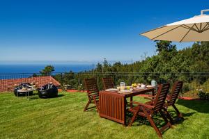 a table and chairs with an umbrella on the grass at Vilas Felicidade Rocha by An Island Apart in Ponta do Pargo