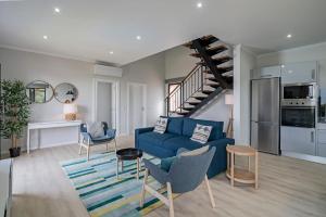 a living room with a blue couch and a staircase at Vilas Felicidade Rocha by An Island Apart in Ponta do Pargo