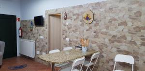 a table and chairs in a room with a stone wall at A Fragua in Tapia de Casariego