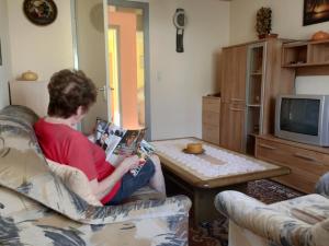 a person sitting on a couch reading a book at Loibl Max in Bad Griesbach