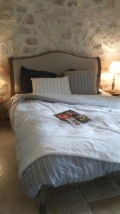 a bed with a white comforter and a lamp at Mas de Karlotte in Pernes-les-Fontaines